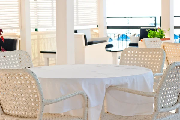 In de cafetaria rieten stoelen en tafels bedekt met doek — Stockfoto