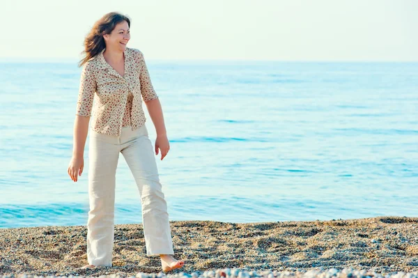 맨발로 해변을 따라 산책 하는 쾌활 한 여자 — 스톡 사진