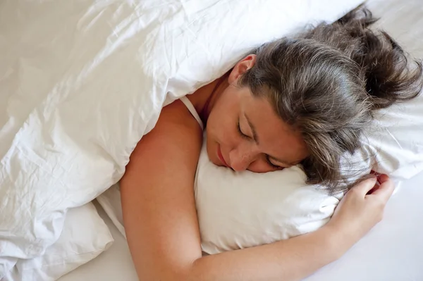 Дівчина спить на животі обіймаючи подушку — стокове фото