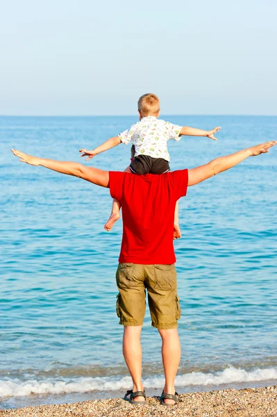 Son sits on his father's shoulders his arms to the side — Stock Photo, Image