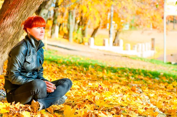 Meisje met rode haren in het park rust in een esdoorn — Stockfoto