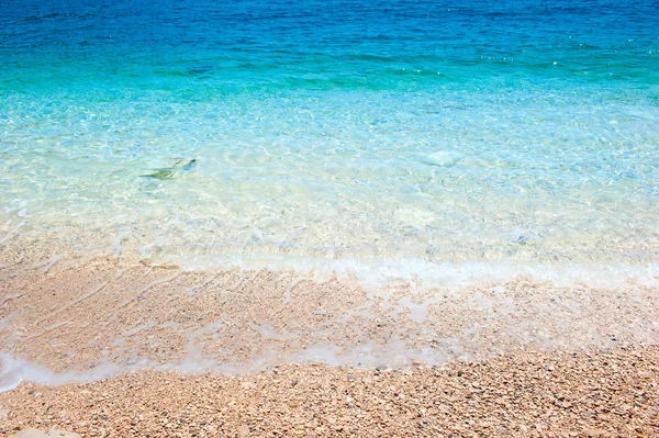 Água do mar limpa rola na costa rochosa — Fotografia de Stock