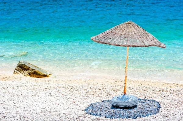 Sombrilla de mimbre en la playa en el borde del agua —  Fotos de Stock