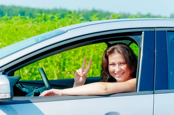 Chica sonriente conduciendo un coche en la naturaleza — Foto de Stock