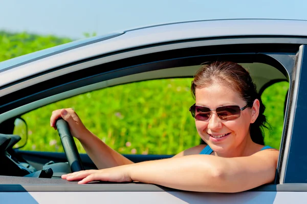 Mujer en gafas de sol conduciendo un coche moderno — Foto de Stock