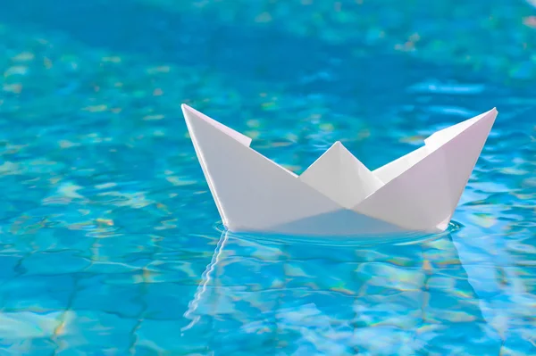 Белая бумажная лодка, плавающая в воде — стоковое фото