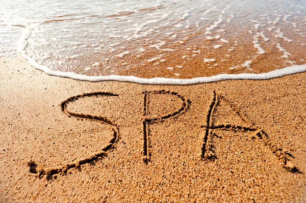 Spa inskriften på sanden nära havet — Stockfoto