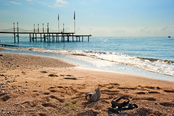 Schoenen op het zand op de kust — Stockfoto