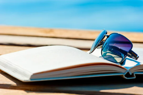 Livro aberto e óculos de sol no fundo do mar — Fotografia de Stock