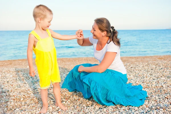 Mother with her son on a pebble beach in the evening — Stock Photo, Image