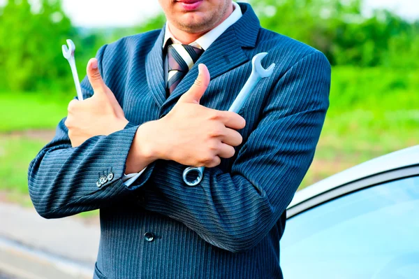 Businessman in a suit holding a wrenches — Stock Photo, Image