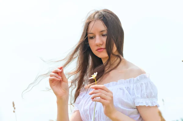 Brunette meisje met een kamille in een hand — Stockfoto