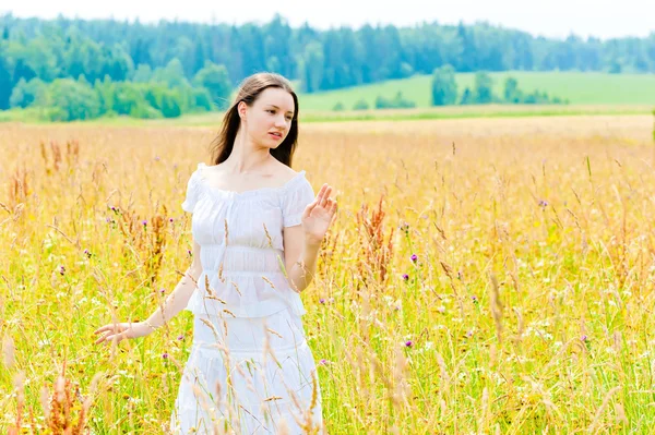 Charmiga brunett i ett fält av gula blommor — Stockfoto