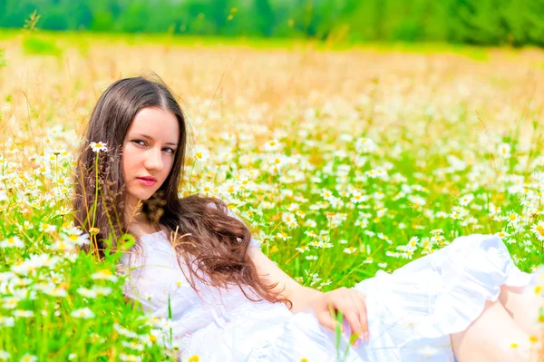 Mädchen ruht sich im Sommerfeld mit Blumen aus — Stockfoto
