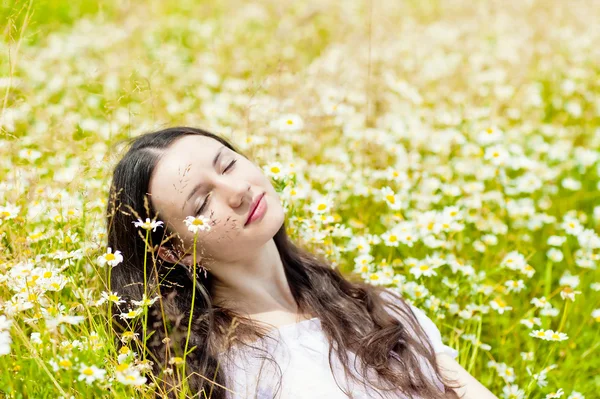 Woman with closed eyes relaxes in daisies — Stock Photo, Image