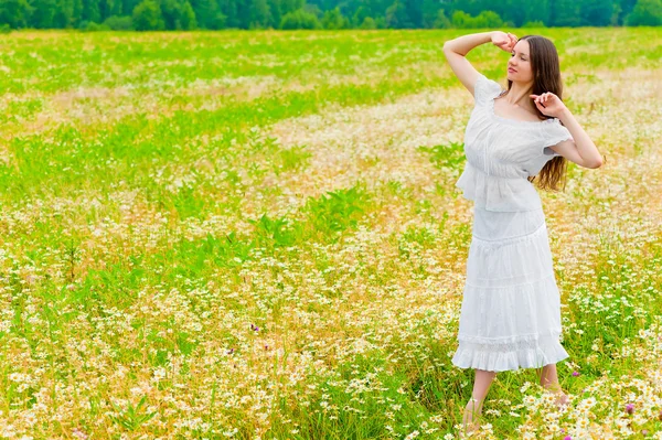 Fiatal barna nő sétál a mező a százszorszépek — Stock Fotó