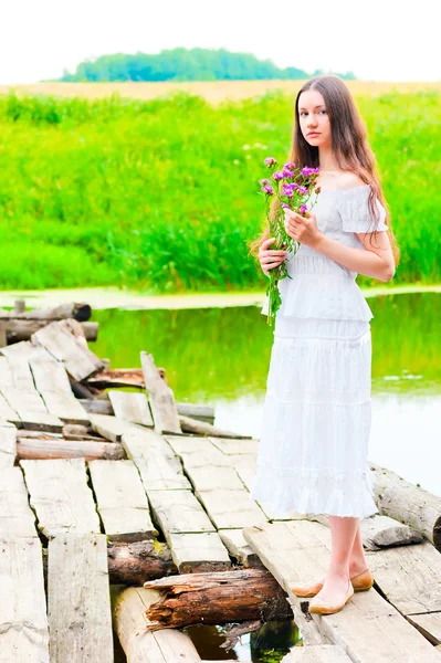 Дівчина на старому дерев'яному мосту з букетом квітів — стокове фото