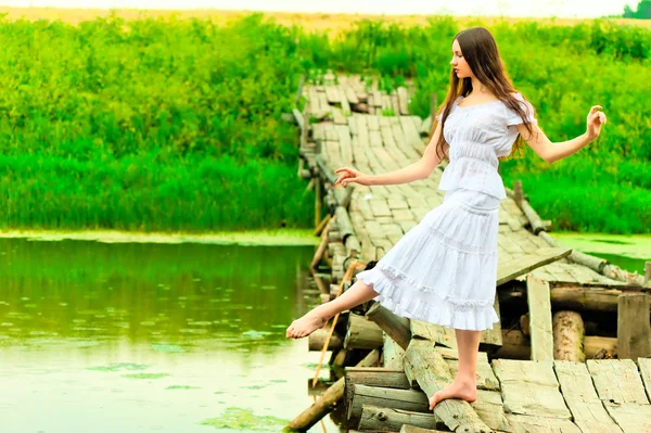 Bela bailarina balanceamento na ponte pelo rio — Fotografia de Stock