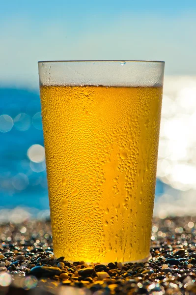 Water druppels op een glas koud biertje op het strand — Stockfoto