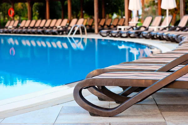 Chaises longues vides pour bronzer et piscine — Photo