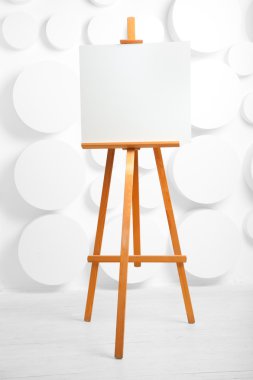 wooden easel with blank canvas in the studio clipart