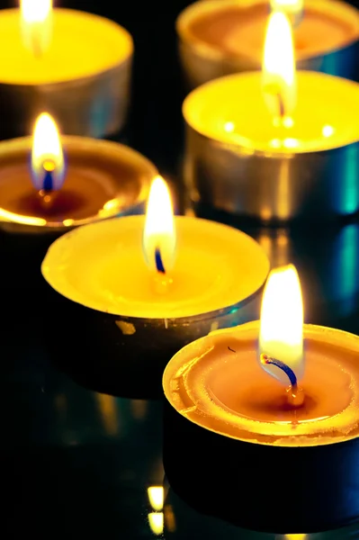 Маленькая желтая горящая свеча в темноте — стоковое фото
