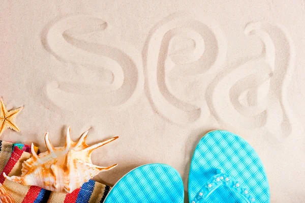 Zee inscriptie op het fijne zand en het strand parafernalia — Stockfoto
