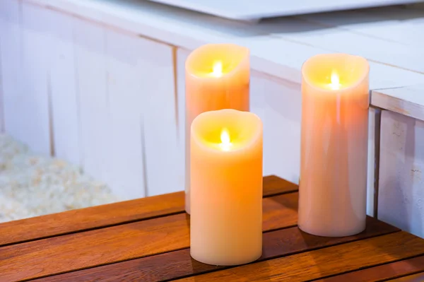 Três velas acesas em uma mesa de madeira — Fotografia de Stock