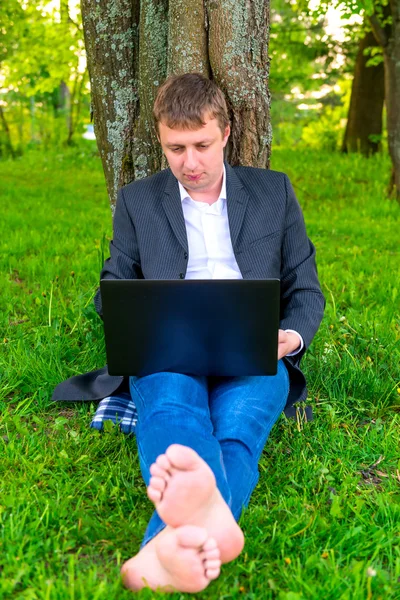 Homem de negócios descalço com um computador no parque — Fotografia de Stock