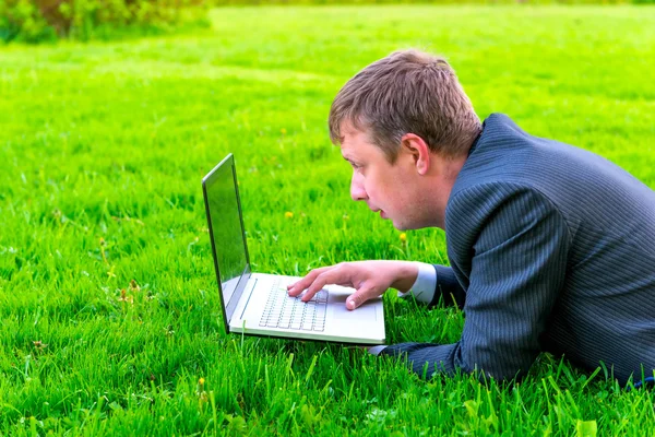Affascinante uomo d'affari si trova sull'erba con computer portatile — Foto Stock