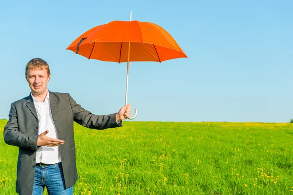 Business man offers a sun umbrella in the field — Stock Photo, Image