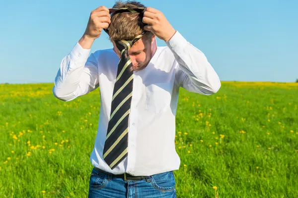 Man wears a tie in the morning in a green field — Stock Photo, Image
