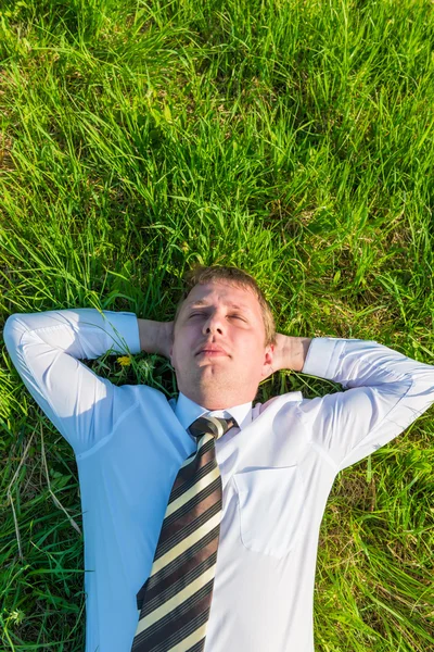 Homem de gravata dormindo no gramado — Fotografia de Stock