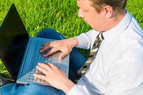 Impiegato lavora sul prato con computer portatile — Foto Stock