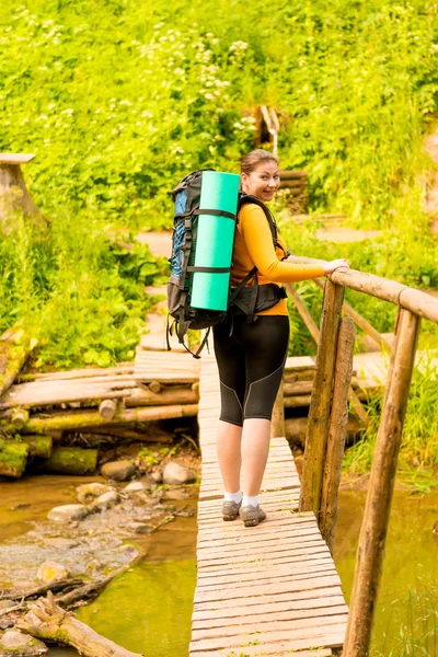 Flicka turist med en ryggsäck i skogen på bron — Stockfoto