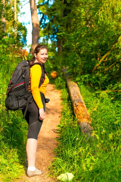 Kvinna med en ryggsäck på en gångstig i skogen — Stockfoto