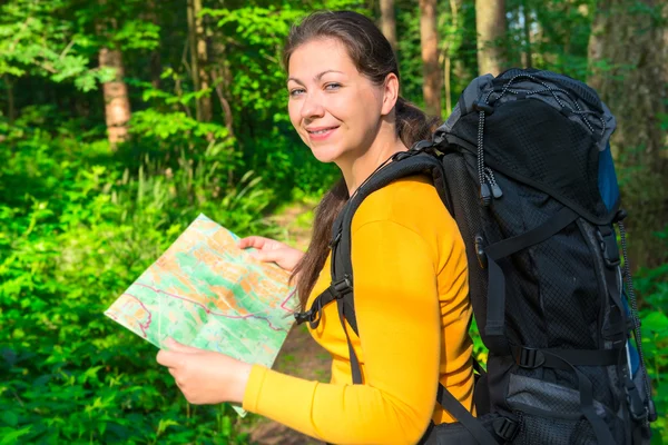 Nöjd resenär med en karta i skogen — Stockfoto