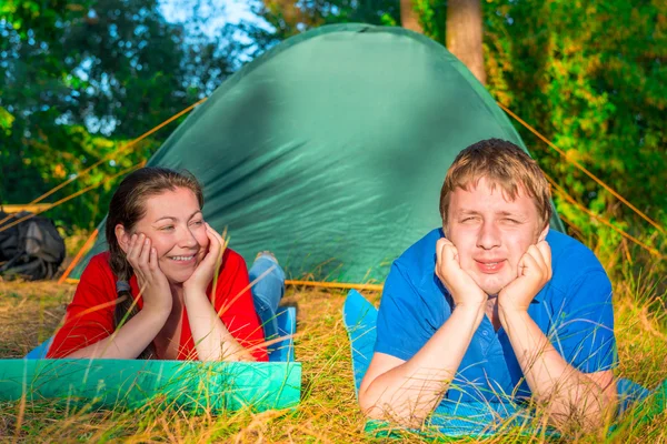 Jonge mensen rusten op het gras in de buurt van tent — Stockfoto