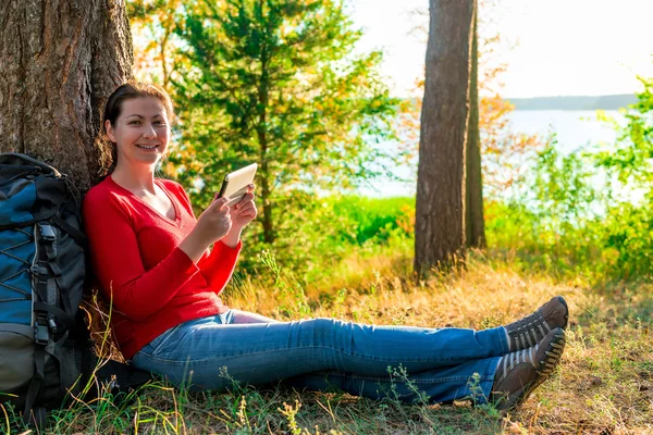 Gelukkig meisje met de Tablet PC rusten in een campagne tegen een boom — Stockfoto