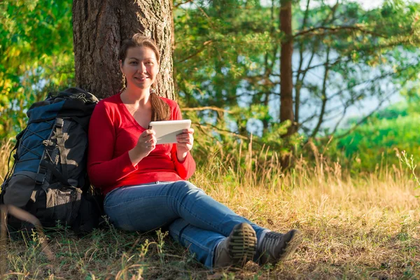 Chica viajero descansando en un árbol con la tableta —  Fotos de Stock