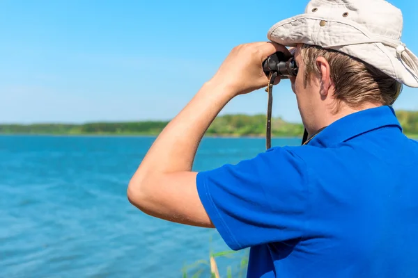 Homem com binóculos procura algo no lago — Fotografia de Stock