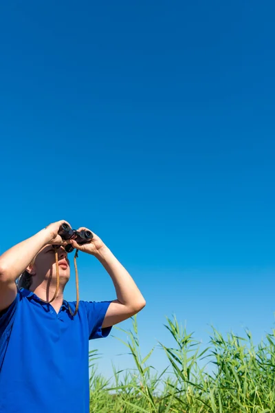 Man looking through binoculars into the sky — Stock Photo, Image