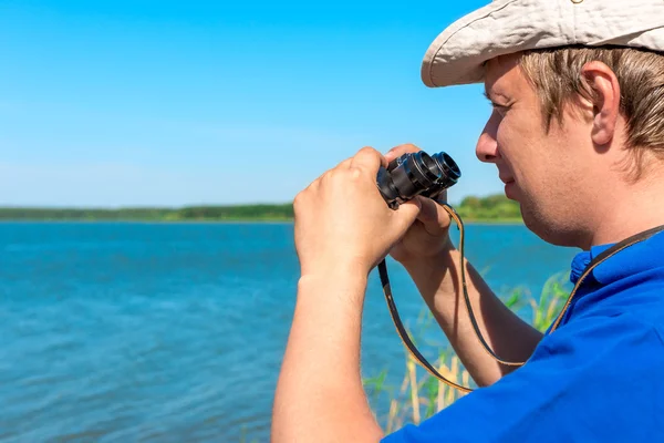 Handsome young man with binoculars at lake — Stock Photo, Image