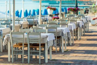 Range of wooden table and white chair for relaxation at restaurant near sea