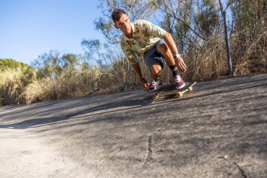 Genç bir kaykaycı ve güneşli bir yaz öğleden sonrasında nehir kanalında numaralar yapıyor.