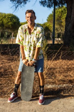 Genç kaykaycı fotoğraf çekilirken gülümsüyor.