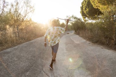 Gün batımında kurak bir nehir kanalında oyuncak bir uçakla oynayan tanınmamış genç adam.