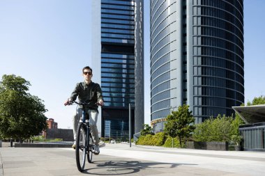 Genç işadamı e-bisikletle ofisinin bulunduğu kuleye gidiyor.