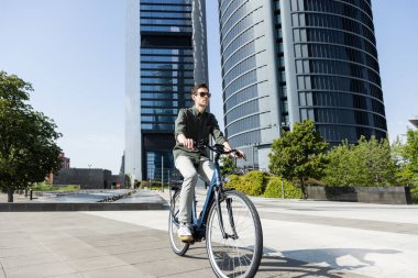 Genç işadamı e-bisikletle ofisinin bulunduğu kuleye gidiyor.