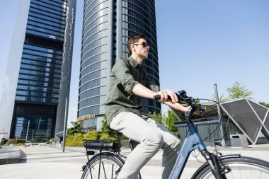 Genç işadamı e-bisikletle ofisinin bulunduğu kuleye gidiyor.